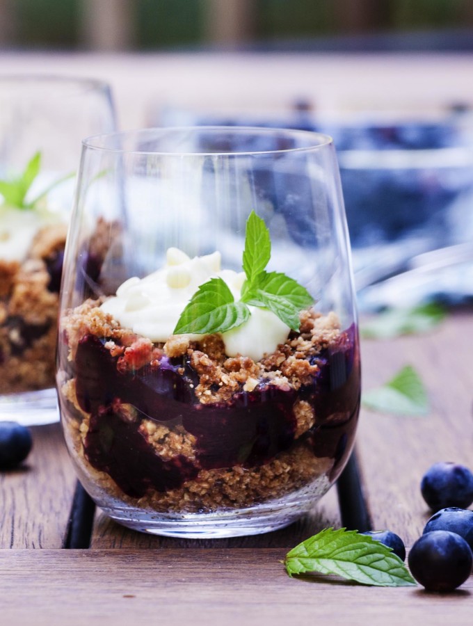 For a great summer dessert, perfect for parties, try this recipe for blueberry parfaits topped with white chocolate cream! Layers of blueberry pie filling and crunchy granola make for a tasty treat. | justalittlebitofbacon.com