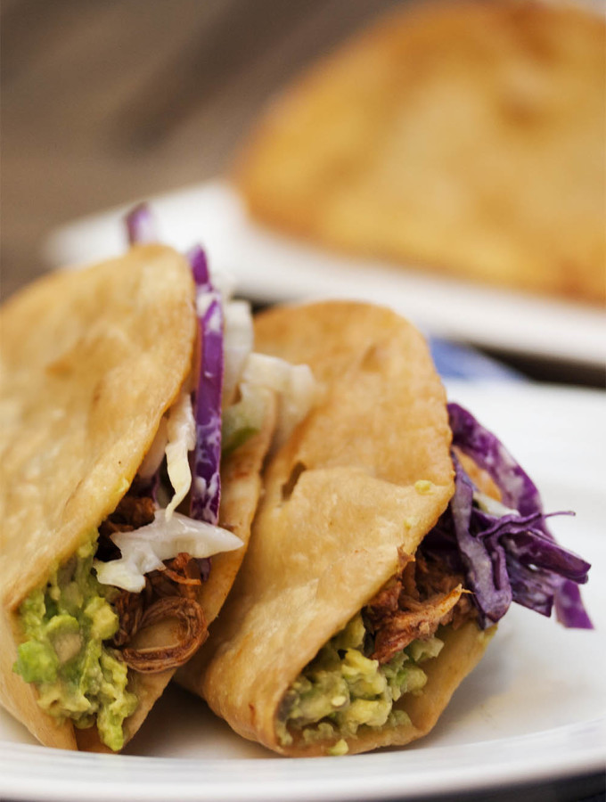 Beer Braised Pulled Chicken Tacos - These tacos feature slow cooked chicken braised in beer and finished with adobo sauce all layered with spicy coleslaw and guacamole. | justalittlebitofbacon.com