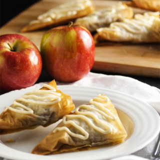 Spiced Honey Apple Turnovers - Layers of flaky fillo dough are wrapped around a filling of apples and honey all flavored with warm spices. Add a drizzle of honey icing on top and you have an apple turnover that will have you wanting more. | justalittlebitofbacon.com