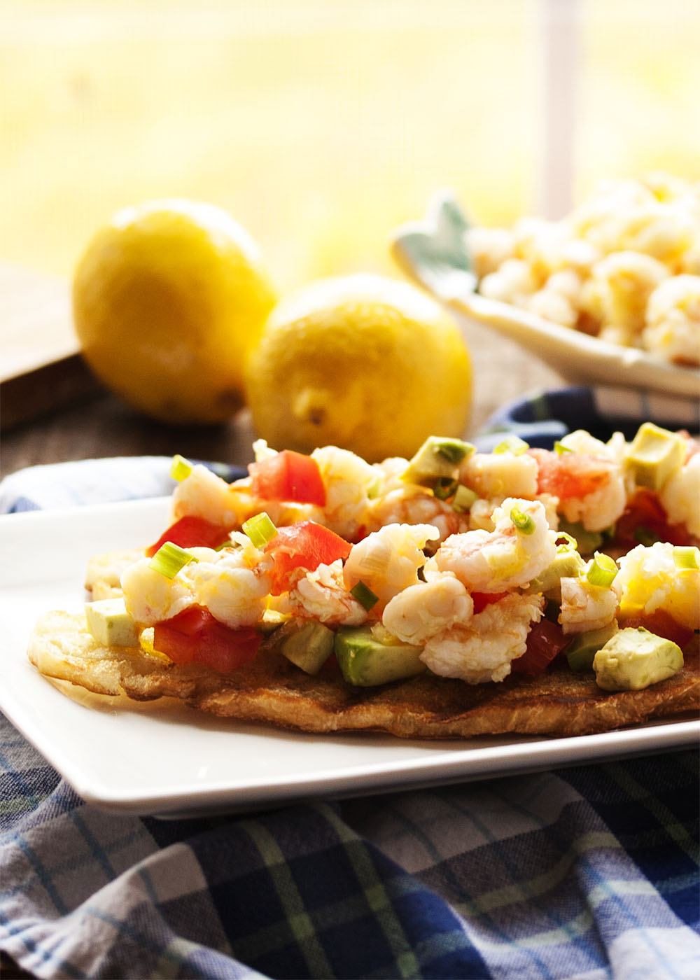 Tomato and Avocado Shrimp Crostini - Beautifully poached shrimp are marinated in lemon and olive oil and paired with grilled bread, diced tomato, and avocado in this Shrimp Crostini. Poaching keeps the shrimp tender and infuses them with flavor. So good! | justalittlebitofbacon.com