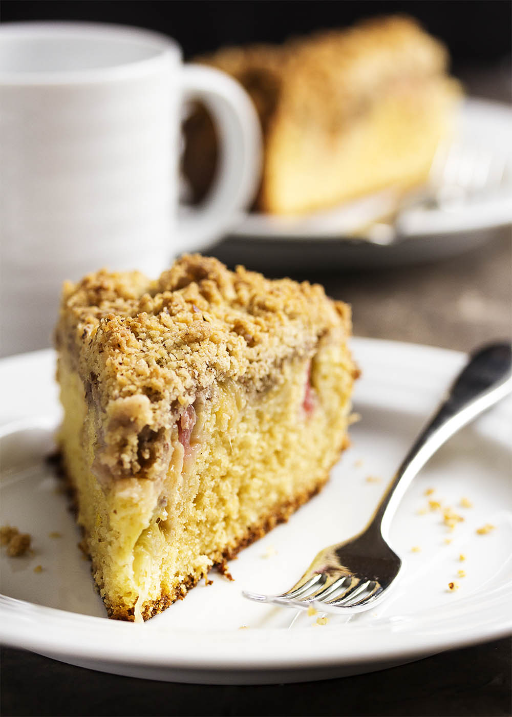 A slice of rhubarb breakfast cake on a plate with a fork.