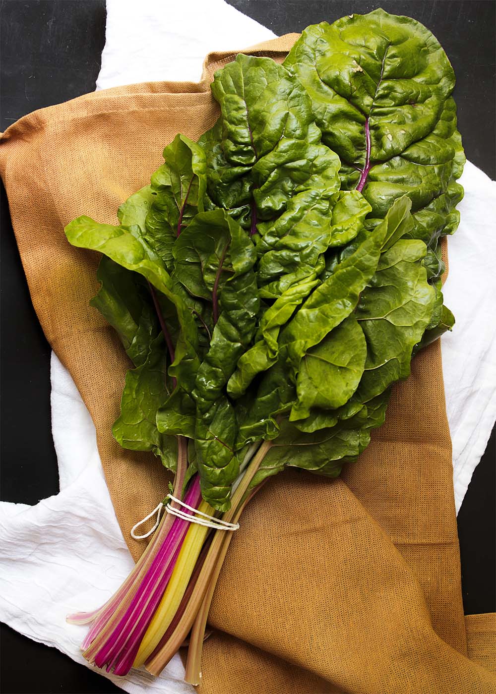 Ingredient Spotlight: Swiss Chard - Swiss chard is a wonderful, hearty green that is great in soups, gratins, pastas, and many other recipes. Its flavor is a cross between spinach and beets and you'll love cooking with it once you give it a try. | justalittlebitofbacon.com