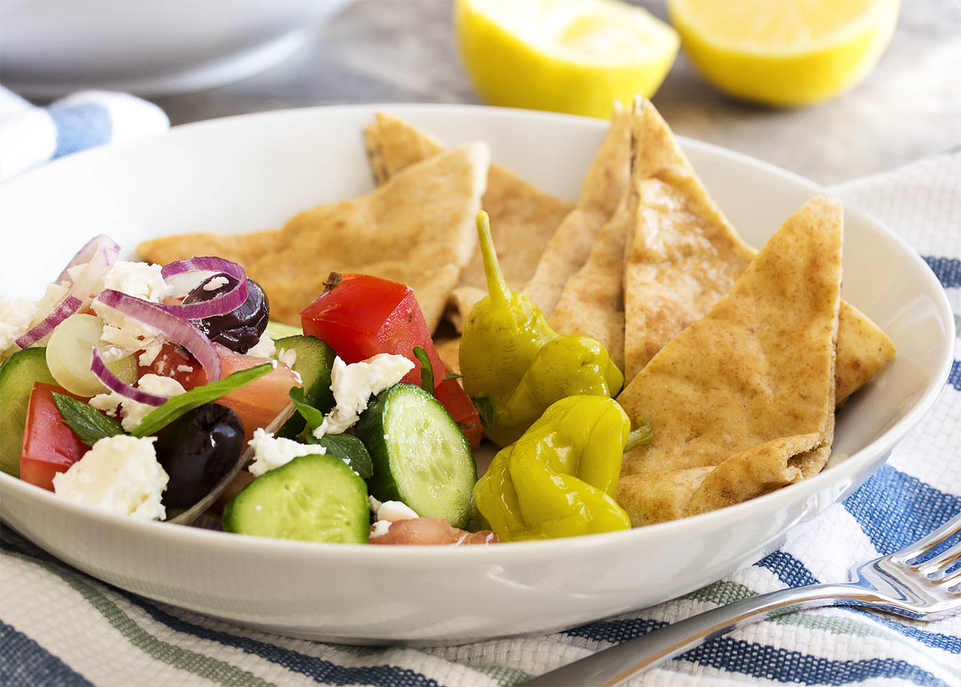 Greek Chopped Salad - Greek chopped salad is a great, healthy Mediterranean recipe full of tomatoes, cucumbers, onion, olives, and feta cheese. I also add in some fresh herbs and toss it all with a lemony dressing. | justalittlebitofbacon.com
