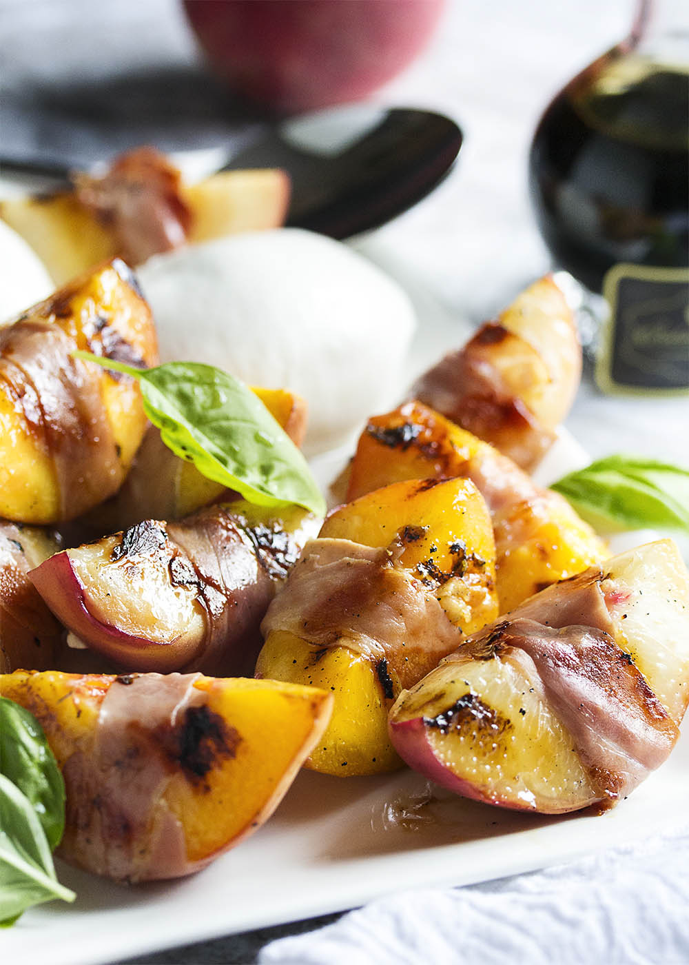 Balsamic Grilled Peaches with Burrata and Prosciutto - Sweet, salty, creamy, and tart combine in this recipe to create a recipe full of bold flavors. Juicy, sweet peaches are wrapped in prosciutto and seared on the grill, then drizzled with balsamic vinegar and paired with burrata. Wonderful as an appetizer or as a side dish. | justalittlebitofbacon.com