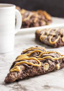 Triple Chocolate Banana Scones - These triple chocolate scones are studded with banana chunks in an intensely chocolatey batter and then topped with chocolate glaze and a peanut butter drizzle. Have them for breakfast or dessert and they would be perfect for a brunch. | justalittlebitofbacon.com