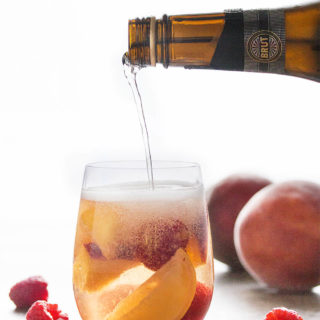 Easy White Peach Sangria - This sparkling white peach sangria is super easy to mix together and just as easy to enjoy on a warm day. Not too sweet and full of fizz from the bubbly, it's the taste of summer in a glass! | justalittlebitofbacon.com