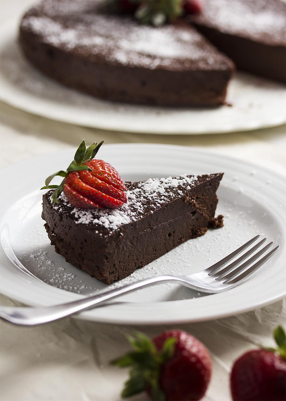 This easy flourless chocolate cake is amazingly dense, rich and decadent. Every bite is packed with intense bittersweet chocolate flavor. | justalittlebitofbacon.com