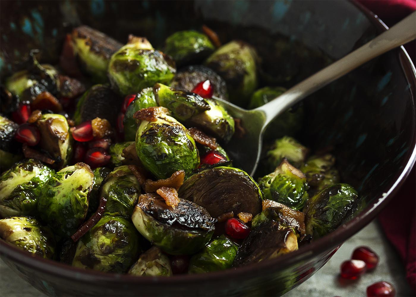 This yummy winter and holiday side dish features pan roasted brussels sprouts, crispy bacon, and sweet pomegranate seeds. Great for Thanksgiving and Christmas or as an easy, weeknight side. | justalittlebitofbacon.com