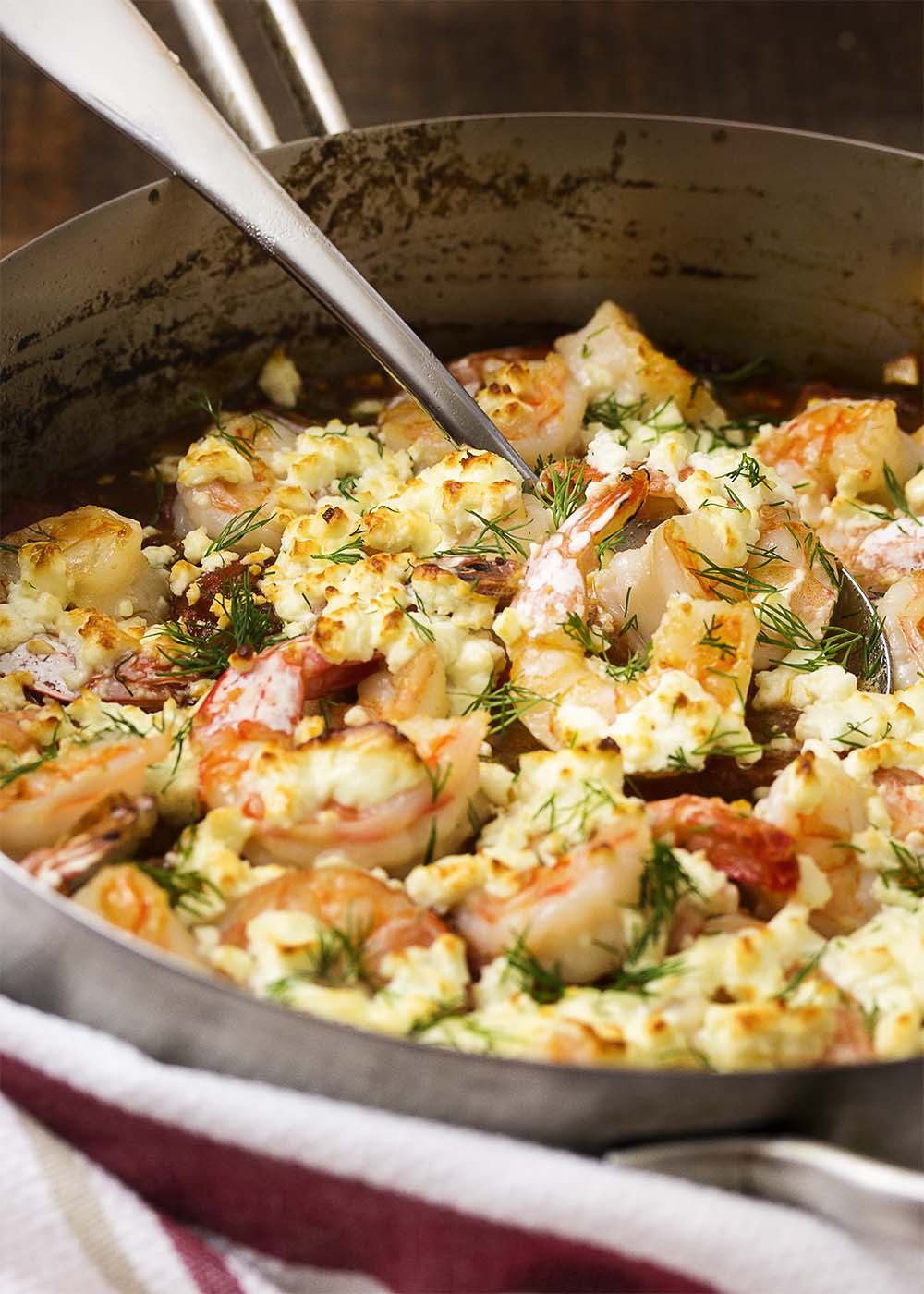 Juicy, plump shrimp are flambeed in brandy then topped with feta before being broiled over a bed of tomatoes in this classic Greek dish! | justalittlebitofbacon.com
