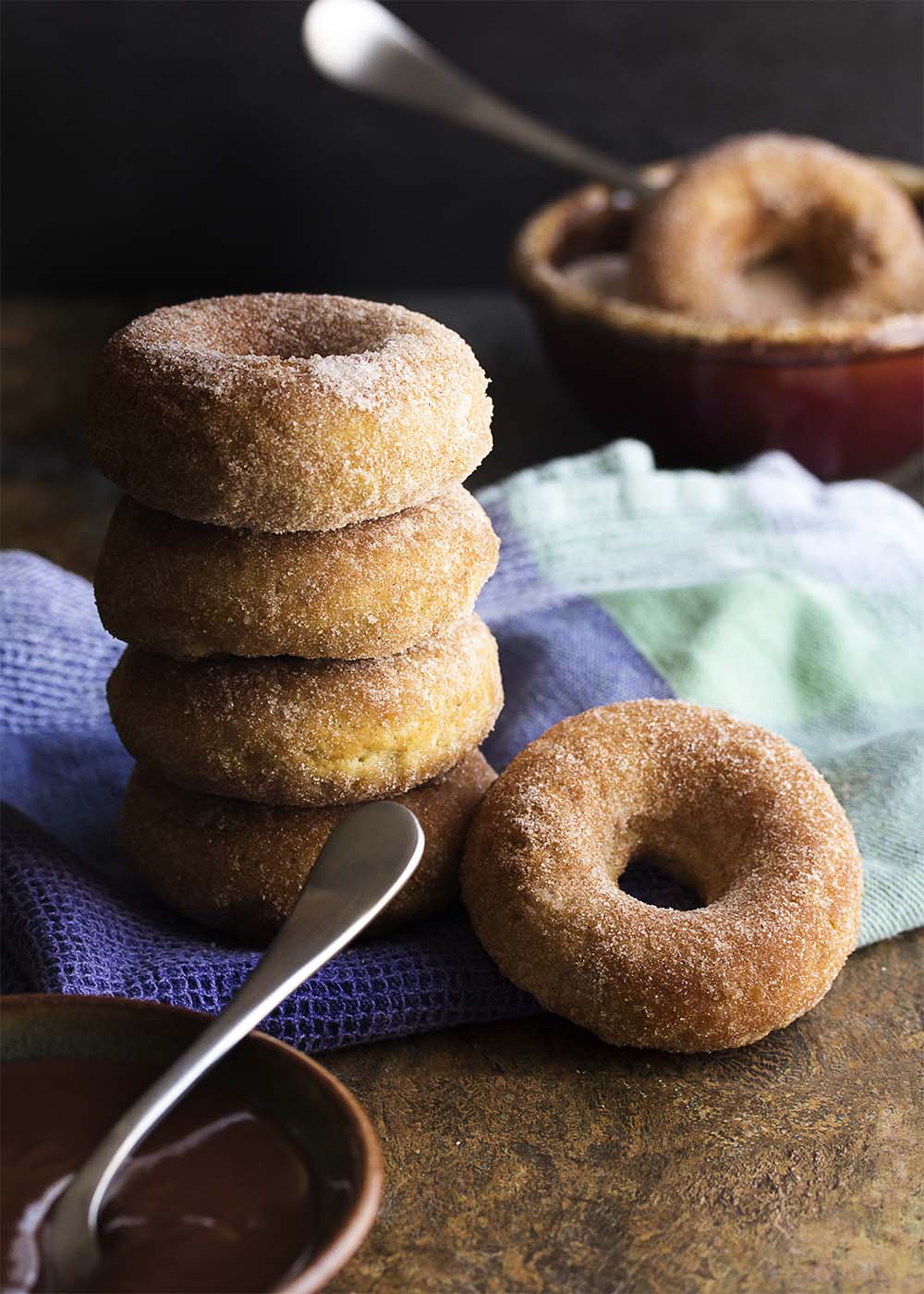 Churros just got a little bit healthier! No deep frying needed. Baked churro donuts are make in a donut pan and rolled in cinnamon sugar. This means you can totally justify the spicy chocolate sauce to dip them in. | justalittlebitofbacon.com
