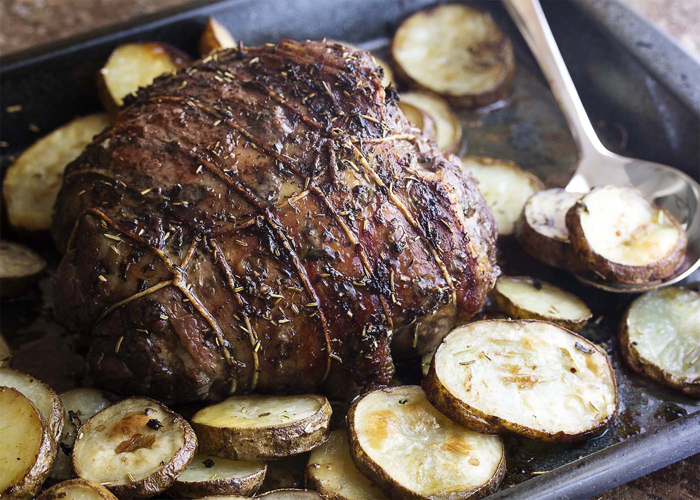 Keep the oven temperature low for a low-stress slow roasted Greek lamb leg which is tender and juicy and pink all the way through! Add some potatoes to the pan for a great, Greek-style meal. | justalittlebitofbacon.com