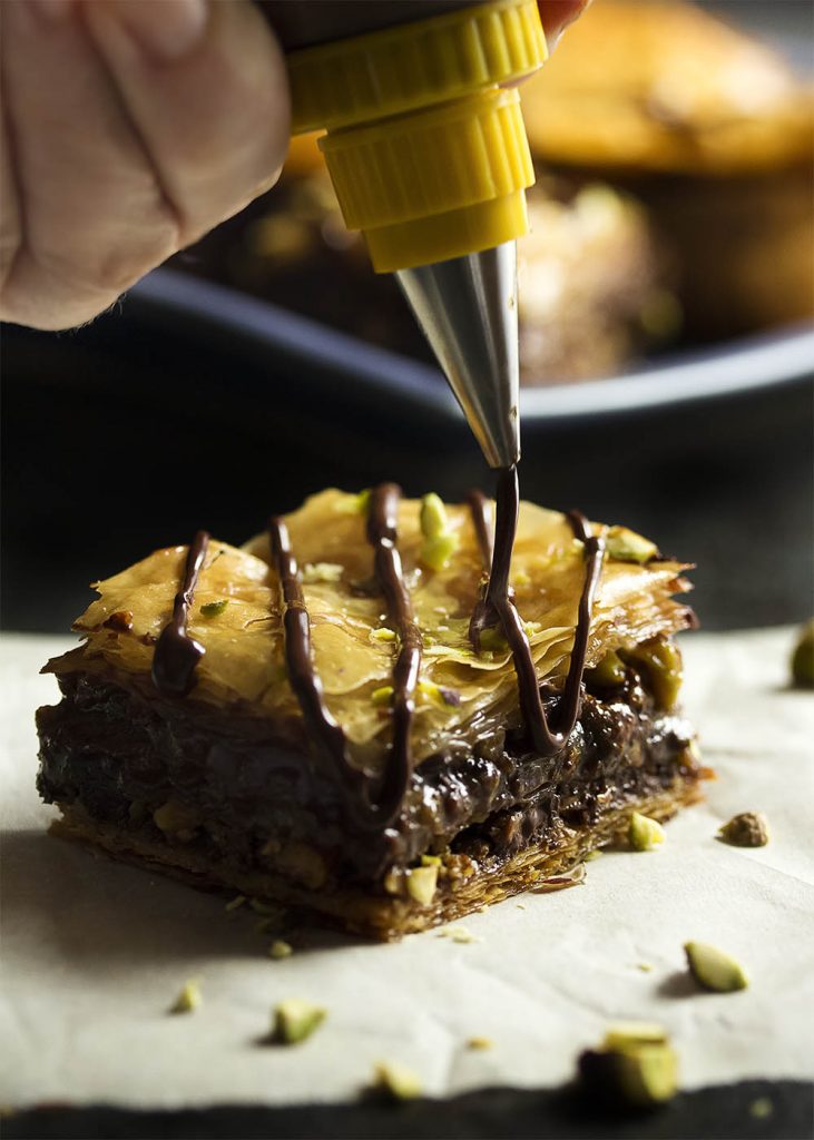 This chocolate baklava is packed full of pistachios and bittersweet chocolate, then drizzled with a honey syrup to make wonderfully rich Greek dessert! | justalittlebitofbacon.com