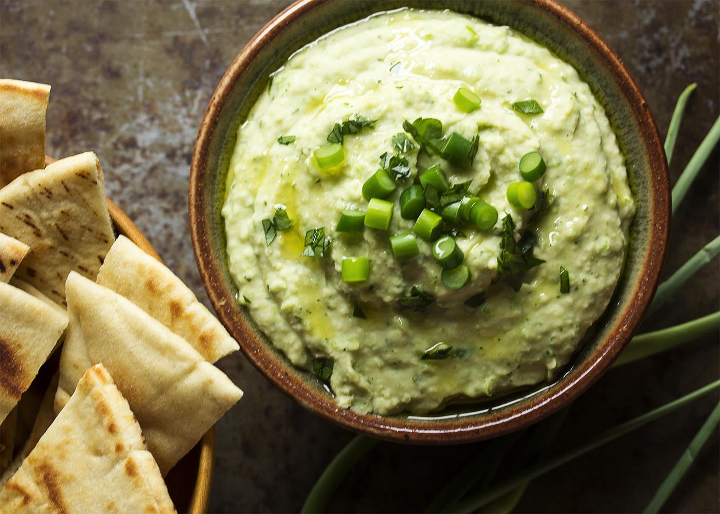 Wondering what to do with garlic scapes? Puree them into a quick and creamy, garlicky bean and garlic scape dip! Great as a healthy snack or for a party! | justalittlebitofbacon.com