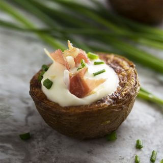 These loaded potato bites make a tasty appetizer for your next party! They are boiled and baked in the oven for extra crispiness and then topped with creme fraiche, pancetta (or bacon!) and chives. Gluten-free, easy, finger food! | justalittlebitofbacon.com