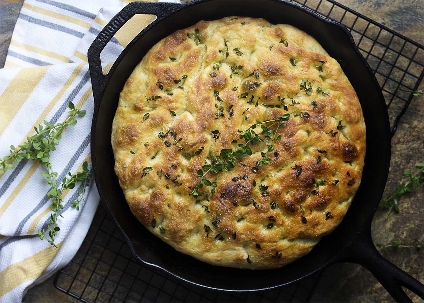 My no-knead focaccia bread with garlic and thyme is made right in a cast iron skillet, giving it a soft and chewy interior and crispy edges. Easy! Great for dinner or for paninis! | justalittlebitofbacon.com