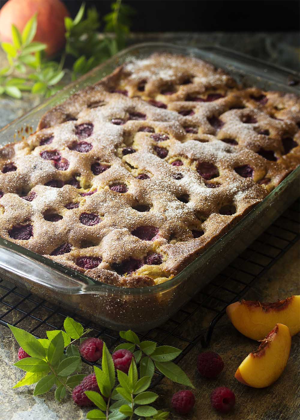 This easy fresh peach cake studded with raspberries is full of fruit flavor, needs no mixer, and freezes beautifully! A simple cinnamon sugar topping finishes it off. Great for breakfast or for dessert. | justalittlebitofbacon.com