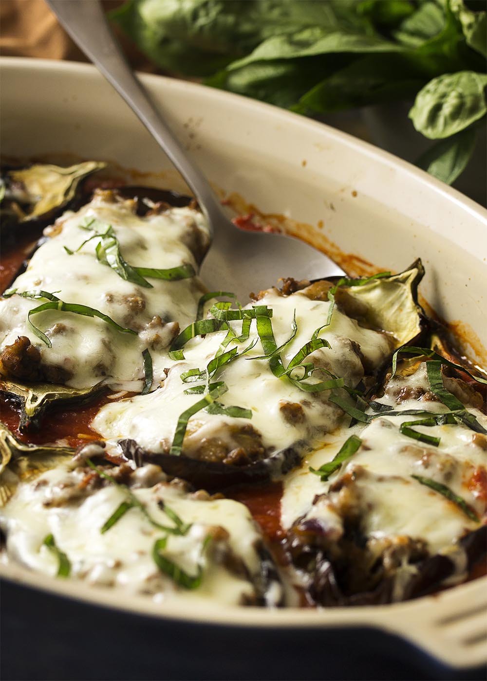 For a fun and tasty way to enjoy eggplant, try stuffed eggplant parmesan! The eggplants are stuffed with ground beef, topped with plenty of mozzarella cheese, and baked in the oven until browned and gooey. Gluten-free. | justalittlebitofbacon.com
