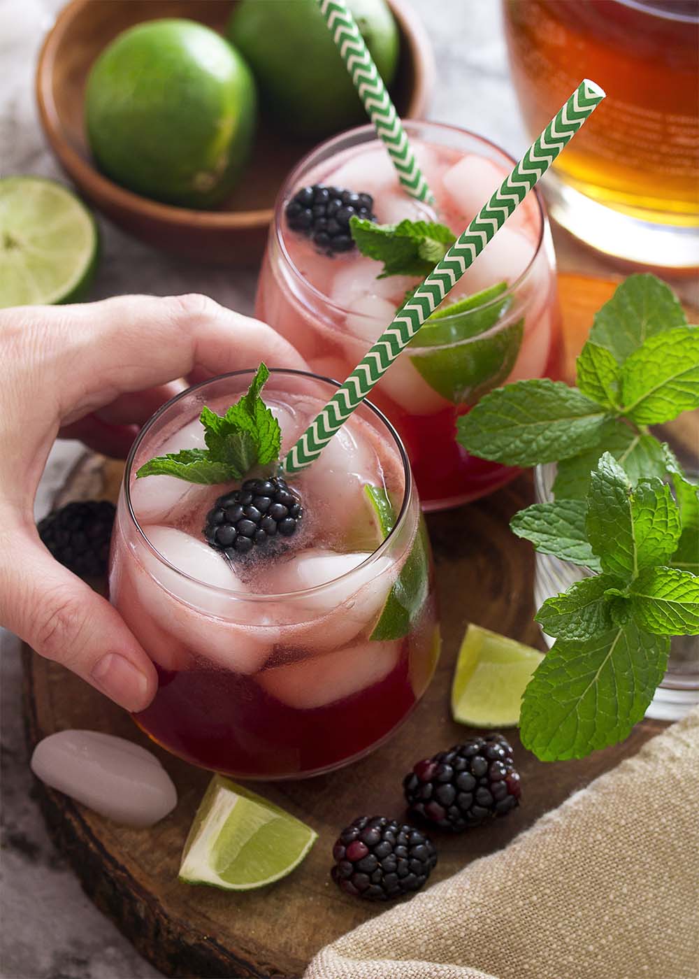 Top view of a hand reaching for a blackberry mojito.