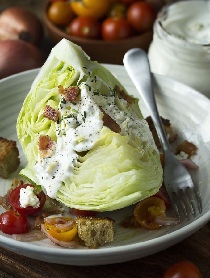 Steakhouse-style classic wedge salad made from iceberg lettuce, topped with buttermilk blue cheese dressing, bacon, and tomatoes is a great dinner side. For date night or for a crowd.