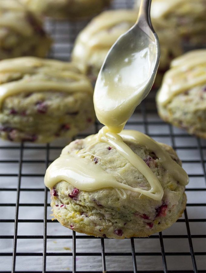 Tender, moist orange cranberry scones combine fresh cranberries and orange zest for plenty of zing and a white chocolate glaze to put them over the top. They make a great holiday treat, perfect to share with friends and family on Christmas morning or Thanksgiving. | justalittlebitofbacon.com #cranberries #thanksgivingrecipe #christmasrecipe #holidayrecipe #whitechocolate #cranberryscones #scones