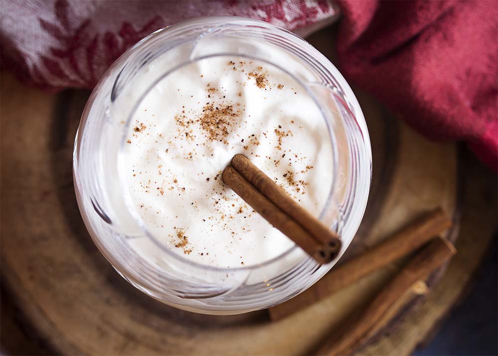 Top view of a glass of hot spiced milk topped with nutmeg and whipped cream.