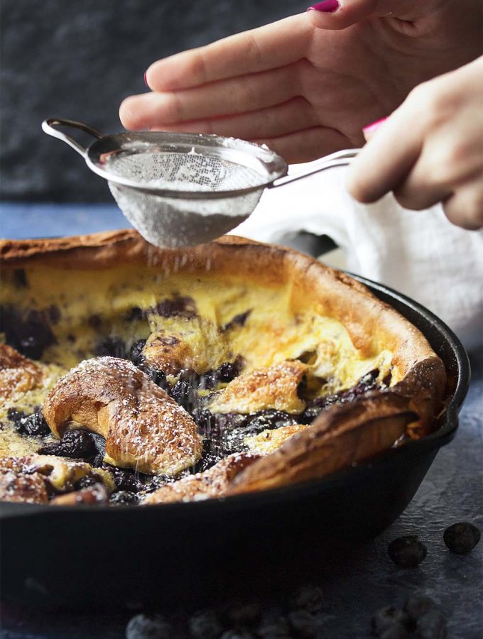 For an easy, yet impressive breakfast pull out your cast iron pan and make a blueberry Dutch baby skillet pancake! Also known as a David Eyre pancake, this puffed breakfast treat is great topped with powdered sugar, jam, or whipped cream. | justalittlebitofbacon.com #dutchbaby #pancakes #castironrecipes #blueberries #breakfastrecipes