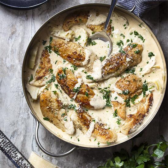 Skillet chicken and artichokes is quick, weeknight comfort food! Chicken tenders are pan seared and then nestled in a creamy white wine and parmesan sauce. Great Italian and Mediterranean flavors! | justalittlebitofbacon.com #italianrecipes #mediterraneanrecipes #chickenrecipes #skilletchicken #chickentenders #chicken #artichokes