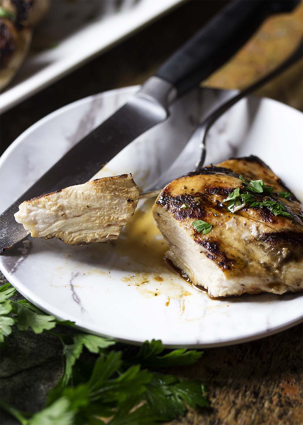 A piece of grilled balsamic chicken cut open showing the juicy, well cooked interior.