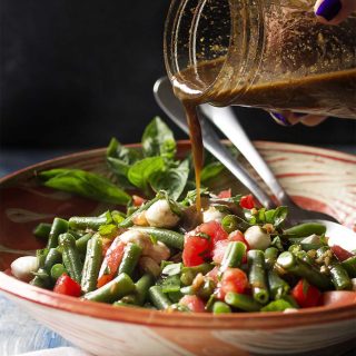 For an easy side dish which makes the most of fresh summer vegetables, you'll love this recipe for a cold Italian green bean and tomato salad! Green beans, tomatoes, basil, and mozzarella are all tossed in a sweet and tangy balsamic dressing. Great for bbqs, cookouts, and family dinners. | justalittlebitofbacon.com #summerrecipes #saladrecipes #greenbeans #italianrecipes #sidedish