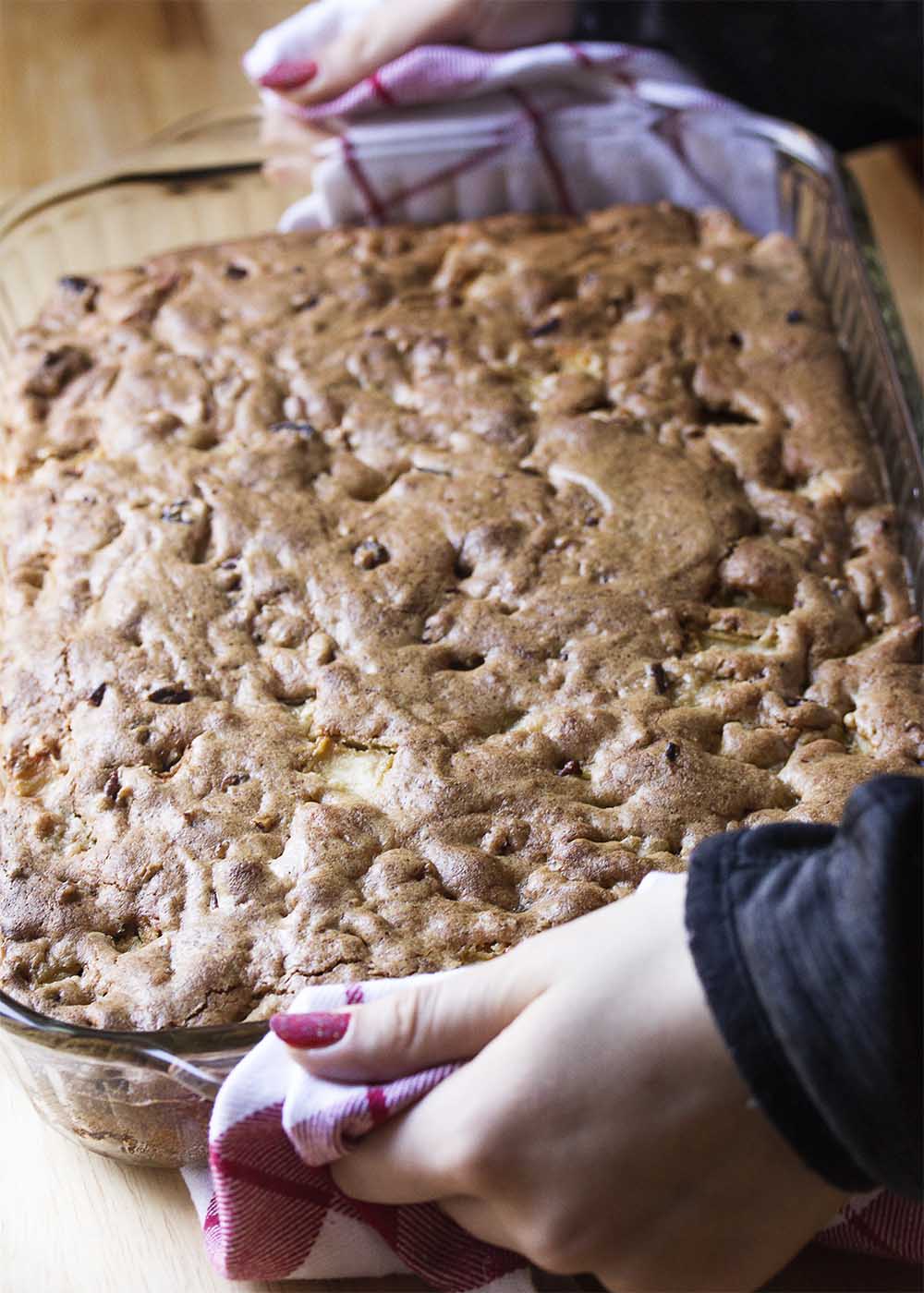 A large baking dish being held up of freshly made cake hot from the oven.