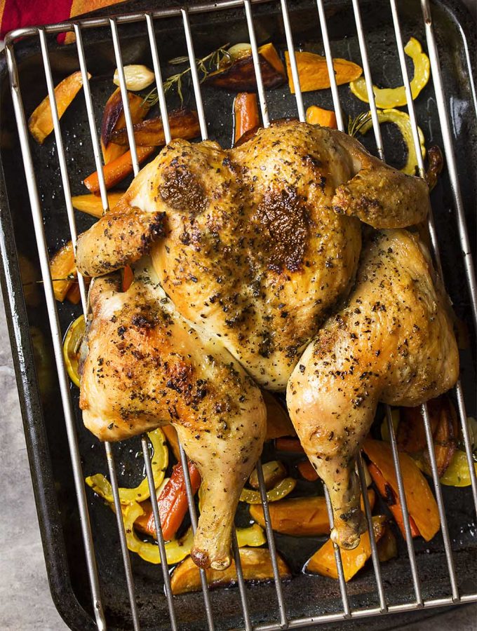 For simple oven roasted whole chicken with crispy skin and juicy meat, try my recipe for roasted spatchcocked chicken along with tender root vegetables! Great for Sunday dinner, Christmas, Thanksgiving, Easter, and any other holidays. | justalittlebitofbacon.com #roastchicken #chickendinner #chickenrecipes #christmasrecipes #holidayrecipes #thanksgivingrecipes