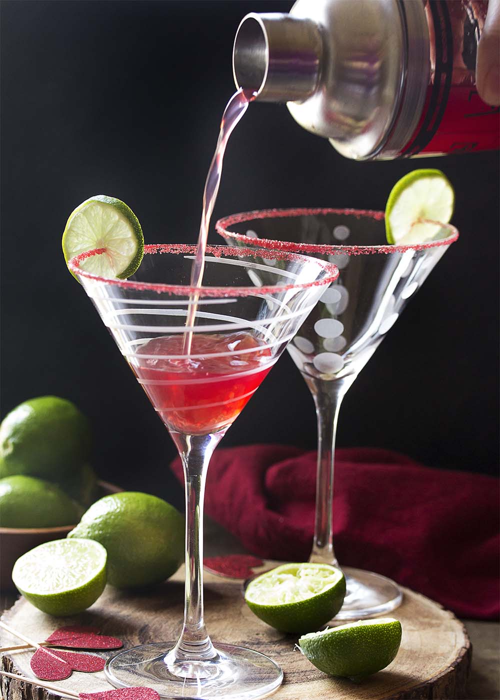 For the perfect holiday drink, try my vodka pomegranate martini cocktail! This easy recipe is well balanced, not too sweet, and simple to make. Great for Christmas, Valentine's Day, or any day you want a little something. | justalittlebitofbacon.com #cocktails #drinks #cocktailrecipes #drinkrecipes #pomegranate #martini #martinirecipes Pouring the cocktail from a shaker into a martini glass.