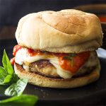 My homemade chicken parmesan burgers are made with ground meat and coated in breadcrumbs to keep them juicy and crispy! Pan fry, top with mozzarella cheese, and a thick tomato sauce for a great family dinner. | justalittlebitofbacon.com #summerrecipes #italianfood #burgers #chickenparm #dinnerrecipes #chicken
