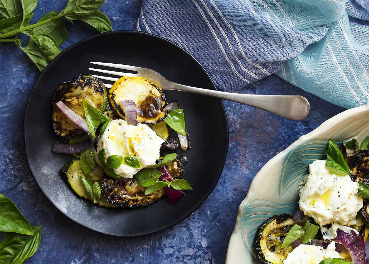 A plate of grilled zucchini salad with lemon ricotta dolloped on top.