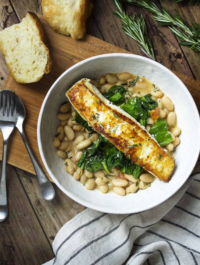 Have dinner in a bowl with pan seared halibut over creamy white beans and sauteed spinach! You'll love that this Mediterranean recipe is healthy, delicious, and quick. | justalittlebitofbacon.com #mediterraneanrecipes #halibut #fishrecipes #dinnerrecipes #easydinner