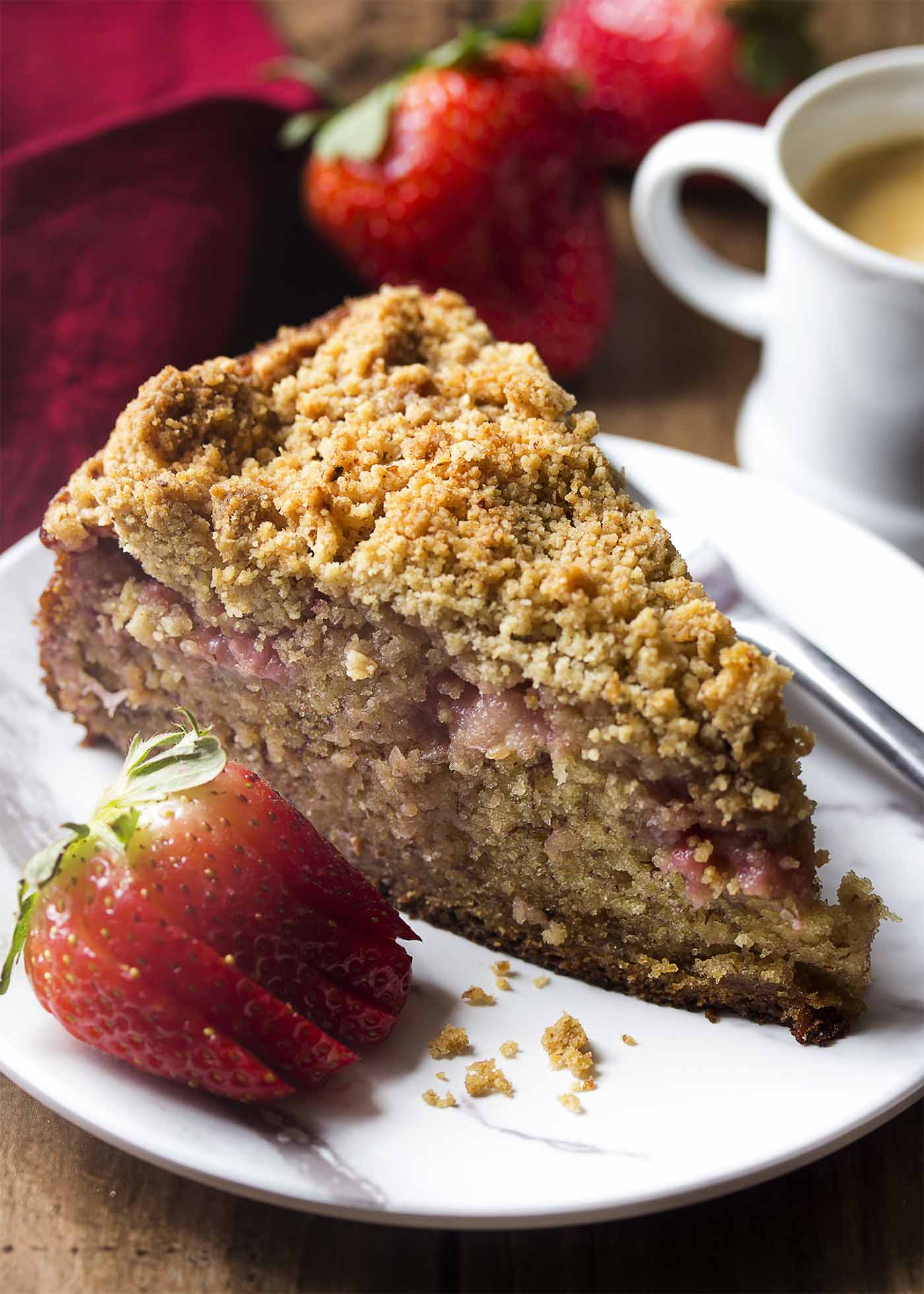 A slice of crumb topped coffee cake on a small plate with a cup of espresso.