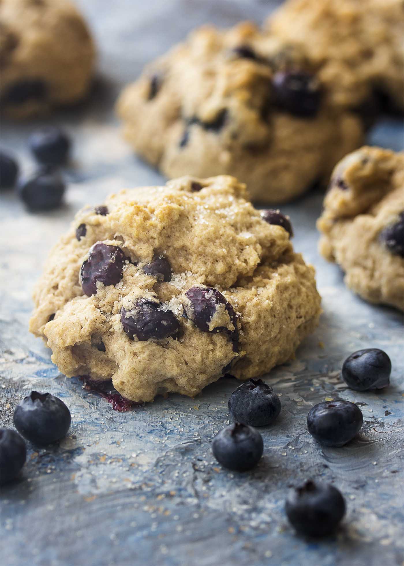 Close up of a drop scone filled with blueberries and topped with coarse sugar.
