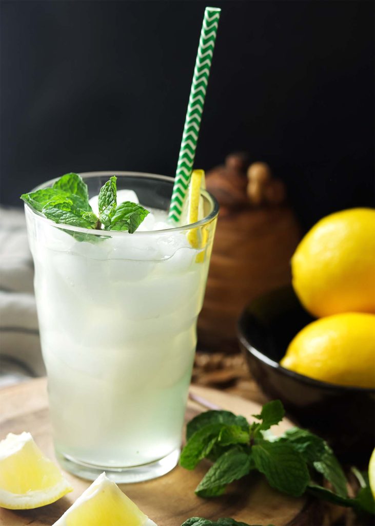 Lemon honey Kyiv mule cocktail in a tall, ice-filled glass with a straw and garnished with mint.