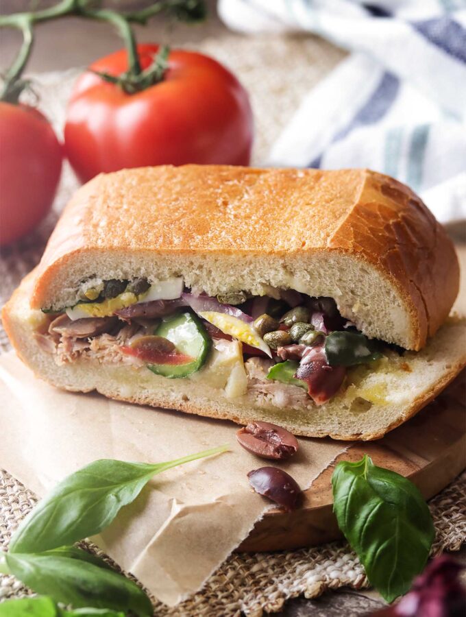 For an easy dinner or packable picnic meal, enjoy a pan bagnat! This French pressed sandwich is Nicoise salad on a baguette, full of jarred tuna, vegetables, and basil, drizzled with a tangy vinaigrette. | justalittlebitofbacon.com