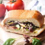 For an easy dinner or packable picnic meal, enjoy a pan bagnat! This French pressed sandwich is Nicoise salad on a baguette, full of jarred tuna, vegetables, and basil, drizzled with a tangy vinaigrette. | justalittlebitofbacon.com
